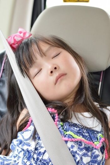 車内でシートベルトにもたれて眠る女の子