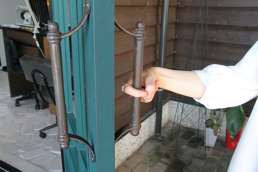 指輪型の非接触グッズ mamotte(マモッテ)をドアノブに引っ掛けて扉を開けるイメージ