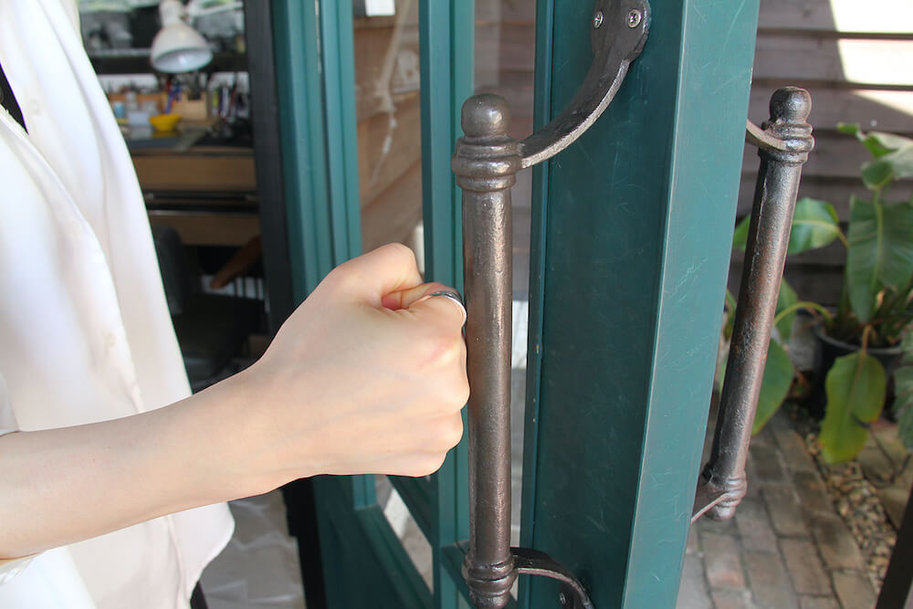 指輪型の非接触グッズ mamotte(マモッテ)をドアノブに押し当てて扉を開けるイメージ