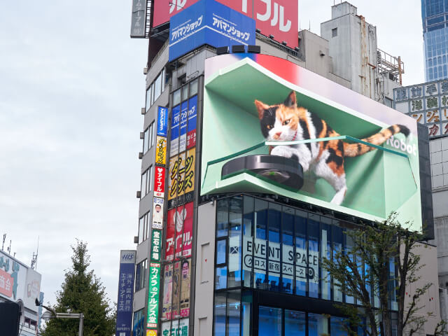ビルの屋上に巨大な3D猫とルンバが出現!新宿駅前の街頭ビジョンでユニークな映像が放映中