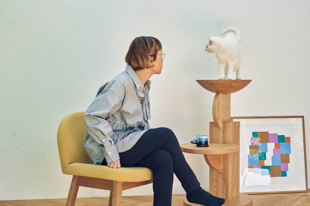 椅子に座りながら猫家具「medel（メデル）」の上にいる猫を愛でる様子