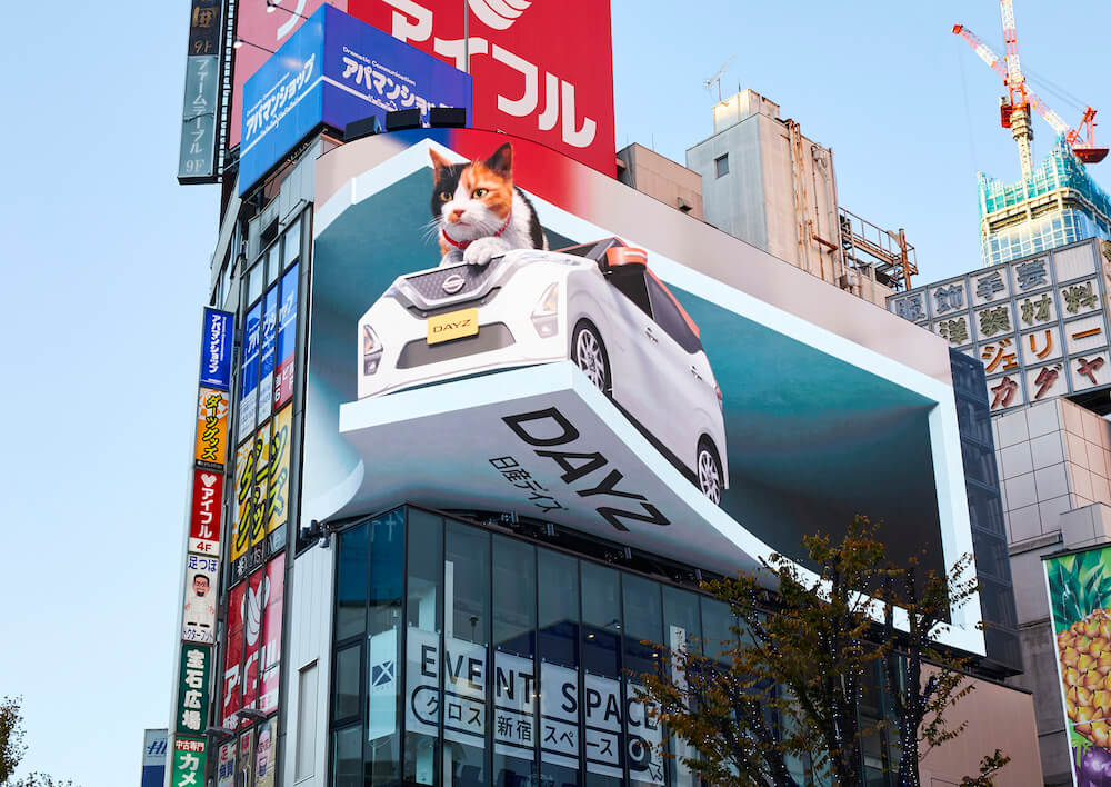 ねこ用軽自動車「にゃっさんデイズ」から通行人に向かって鳴く巨大猫 by クロス新宿の街頭ビジョン