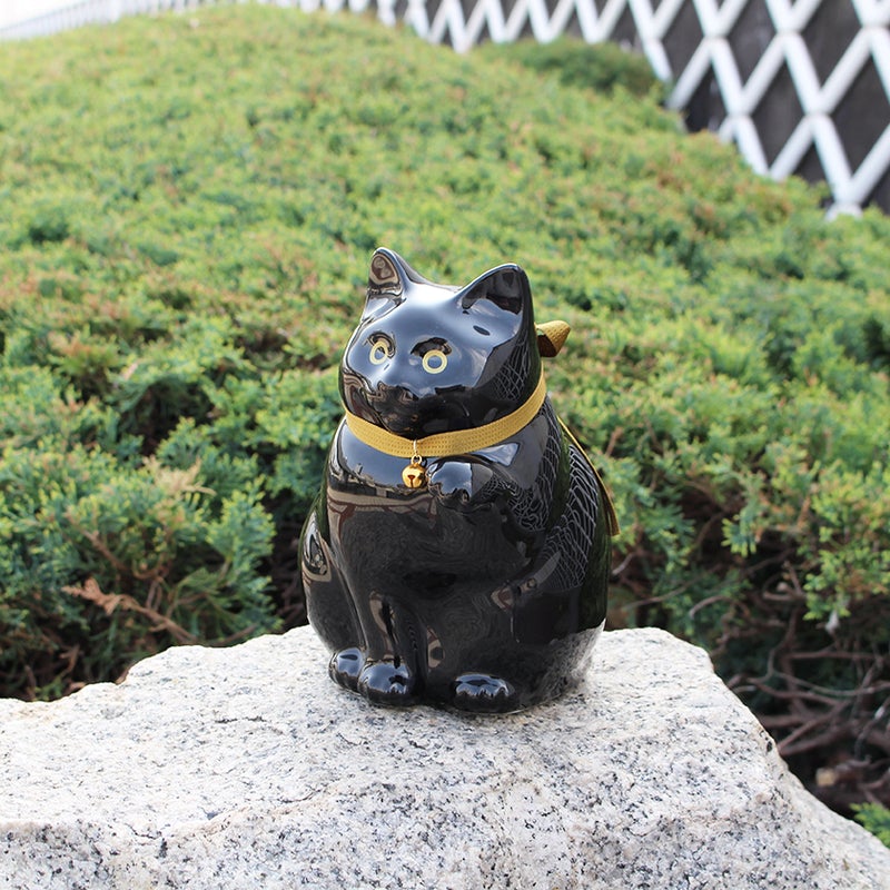 肥前吉田焼の招き猫型貯金箱（ブラックカラー）を屋外に飾ったイメージ by KataKoto（カタコト）