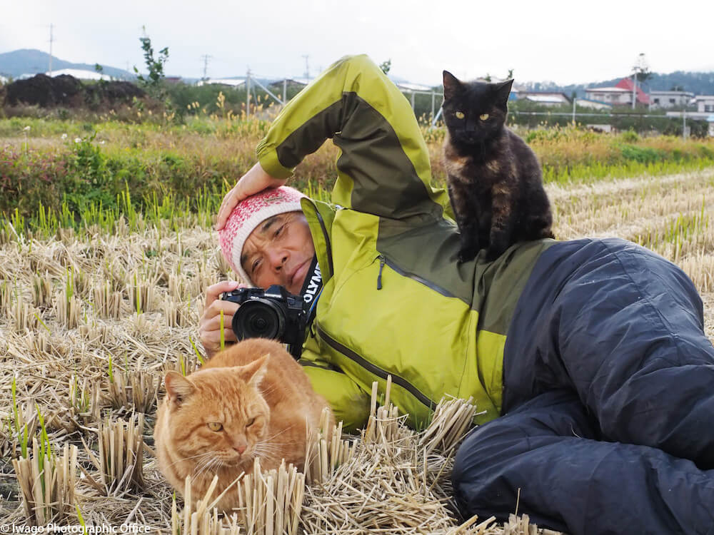 地面に横たわって猫を撮影する岩合光昭さん