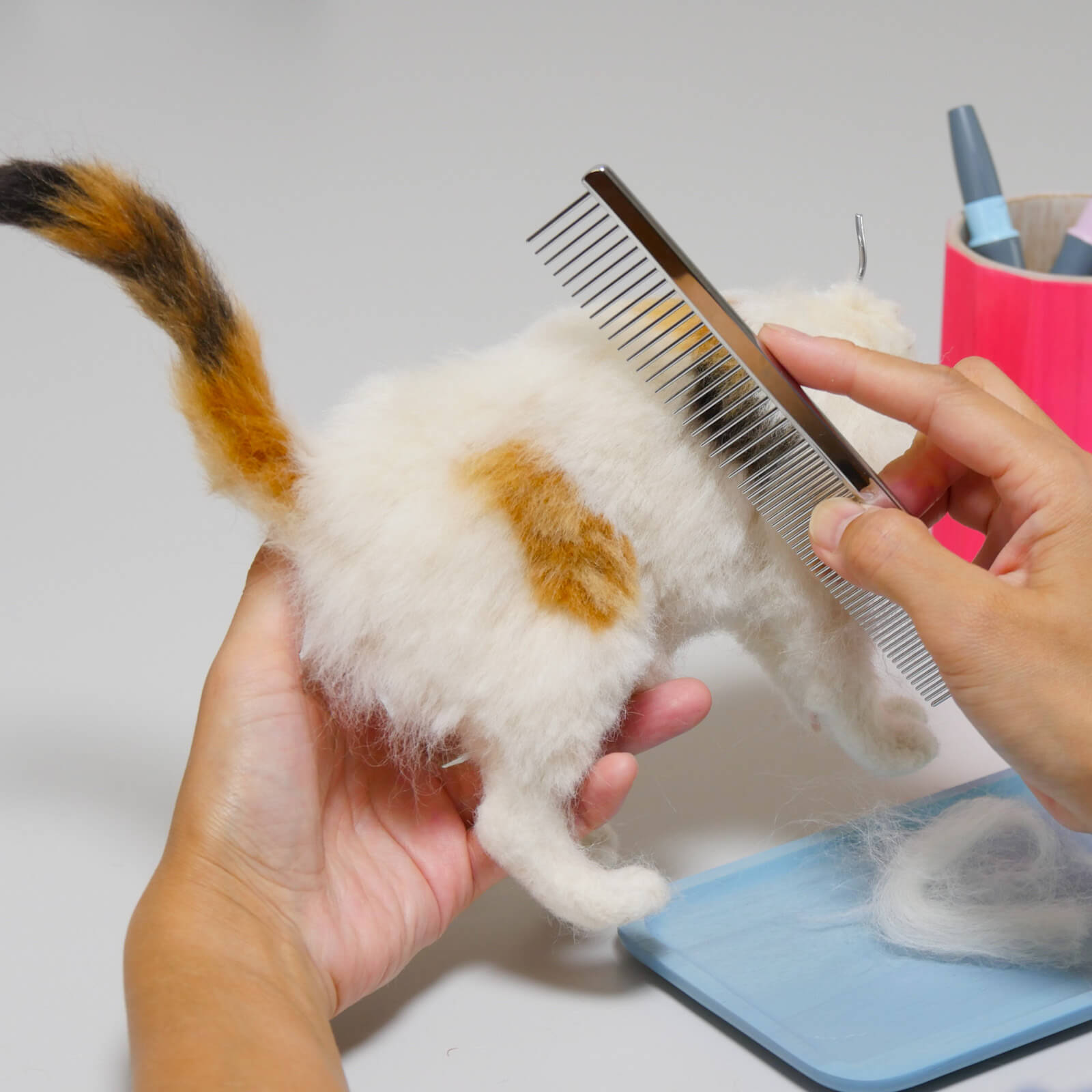 羊毛フェルトで作った猫の体にブラッシングして毛並みを整えるイメージ